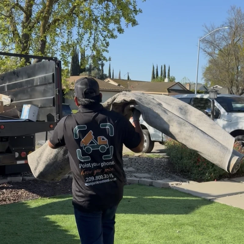 ScanJunk crew carrying rolled carpet for removal in Stockton