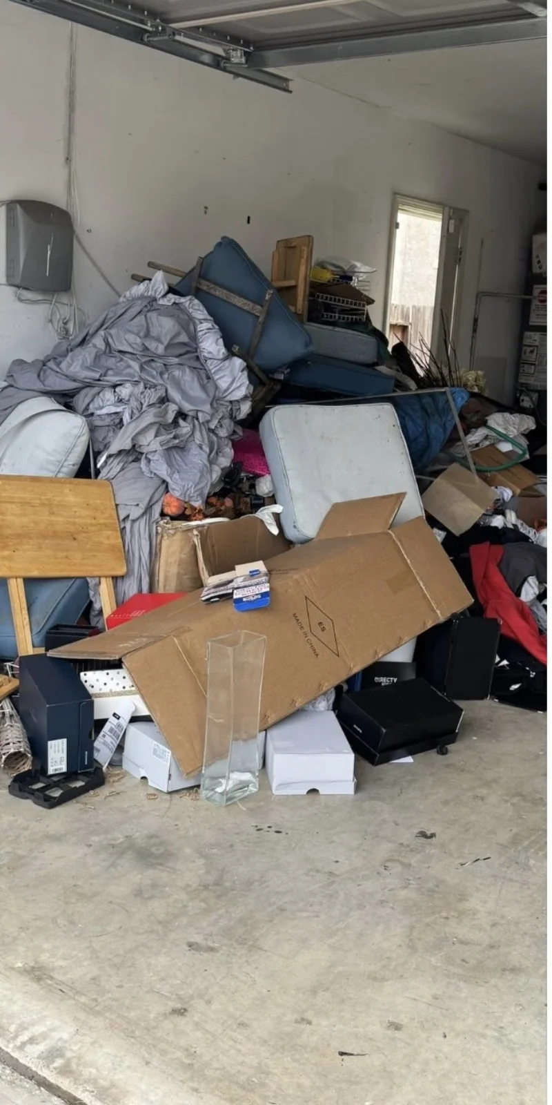 Garage full of junk furniture mattresses and boxes before cleanout in Stockton
